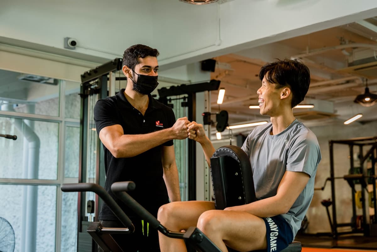 Coach and client sharing a relaxed fist bump during a gym session